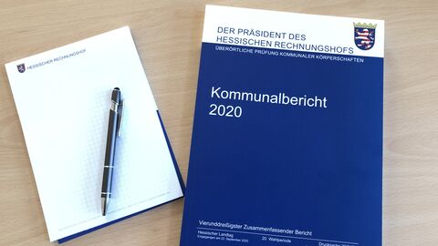 Kommunalbericht 2020 liegt neben einem Block mit Stift auf dem Tisch.