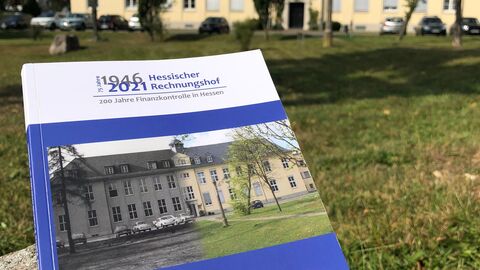 Das Jubiläumstaschenbuch vor dem Gebäude des Hessischen Rechnungshofs