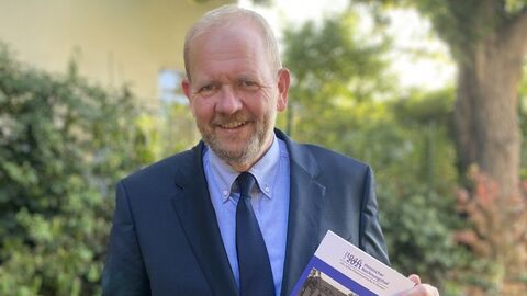 Präsident Wallmann mit dem Jubiläumstaschenbuch in der Hand