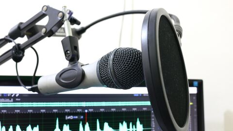 Rundfunk Mikrofon und ein Ausschnitt eines Bildschirm mit einer Tonspur